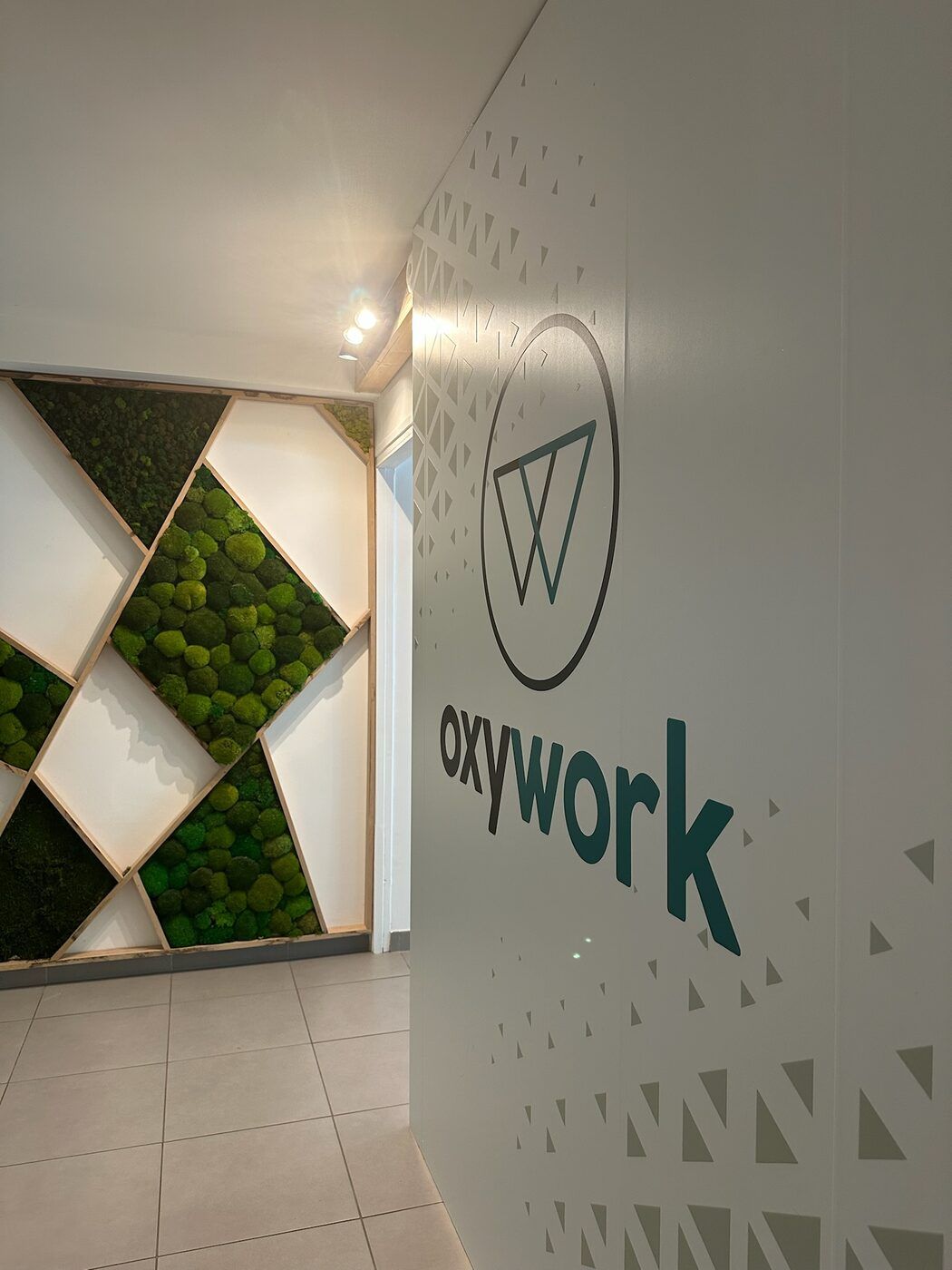 Le hall d'accueil d'Oxywork : un mur de mousse végétale stabilisée en losanges, face à la cloison portant le logo Oxywork